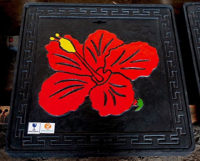 Manhole cover dengan motif bunga sepatu berwarna merah